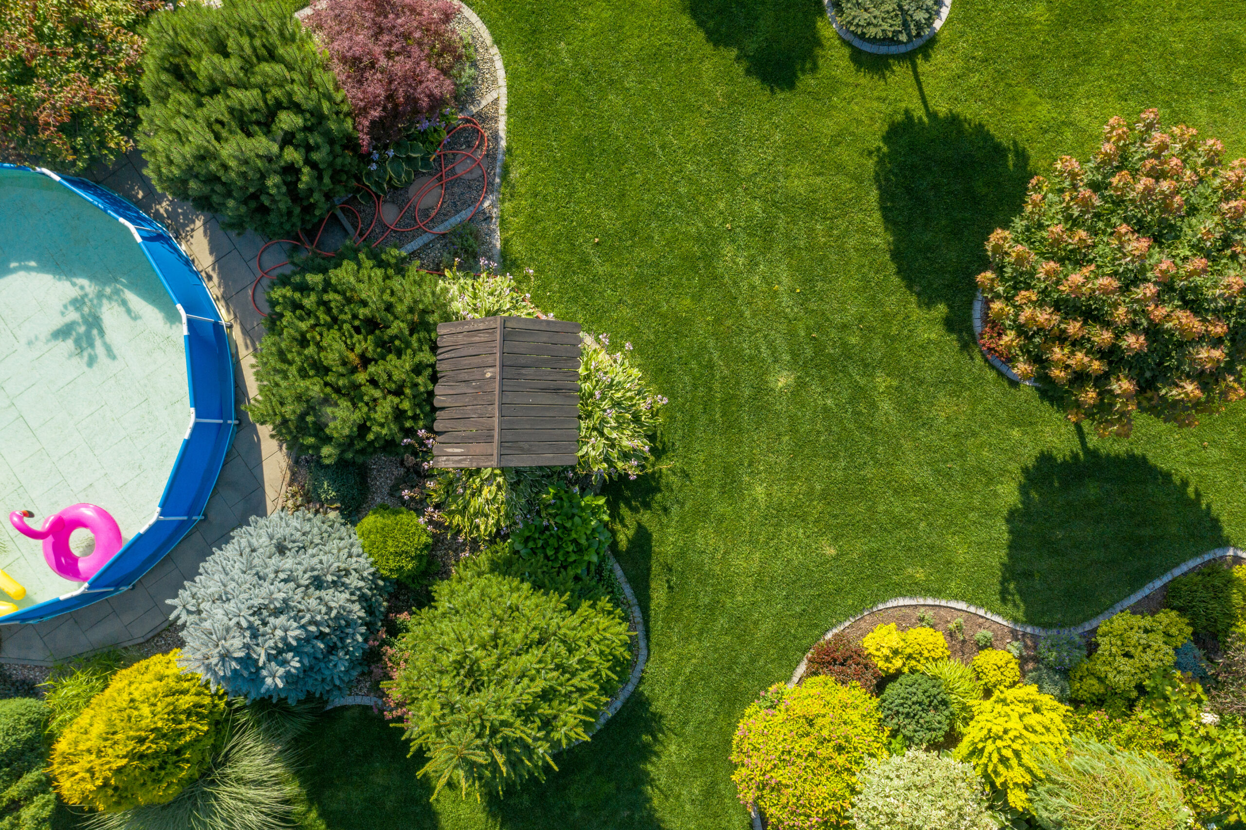 Gardening and Landscaping Industry. Residential Backyard Garden with Small Swimming Pool From Above Aerial View. Summer Time.
